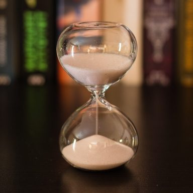 Eine Sanduhr mit transparentem Gehäuse, die sandfarbenen Sand zeigt.